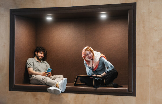 Multicultural employees playing games and having fun during berak at work sitting in recessed wall area