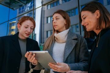 Three businesswomen working on the tablet outdoors