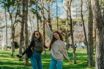 Lovely young girls, curly haired and brunette, posing for the camera while hanging out in the park on a beautiful sunny day