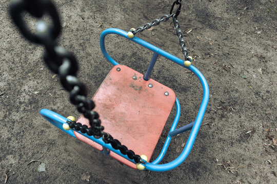 Empty old swing on chains. An old swing in an abandoned playground