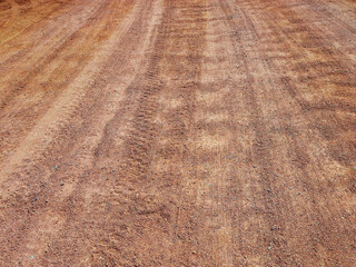 Unpaved road texture. Rough background of vehicle tracks on wet sand. Rough sandstone road background.
