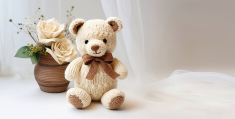 A knitted crochet teddy bear present with a brown bow and a flower pot with white roses against a soft white background with copy space for text - Generative AI