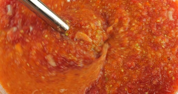 The process of making cold Spanish gazpacho soup. Blend raw vegetables until smooth with an immersion blender.