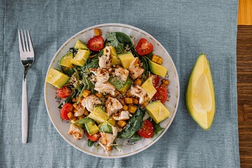 Top view of a healthy gourmet salad with lettuce, chicken, avocado, banana and cherry tomato