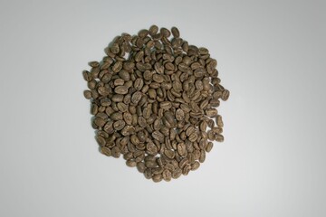 High-angle shot of raw, dried coffee beans, laid out on a plain white background