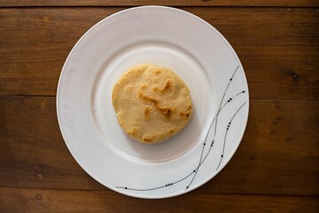 Traditional Venezuelan arepa, a golden-brown corncake, presented on a white plate