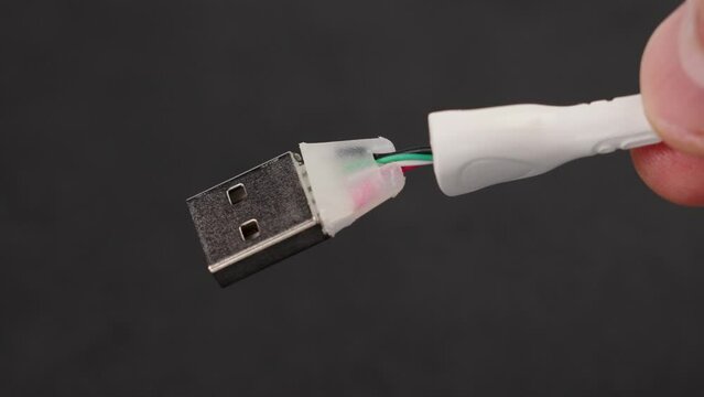 Torn damaged usb cable in hand. The connecting accessory of the smartphone and charging is broken