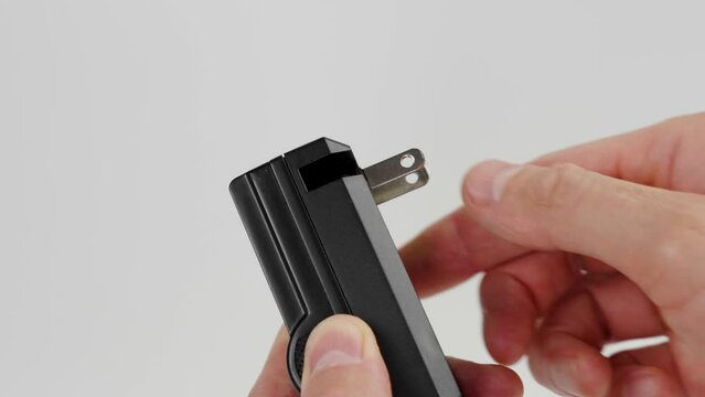Portable folding electric charger plug opening by hand on white background close up. Foldable american electric power supply contactor