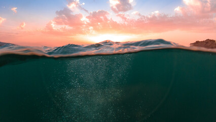 Underwater part and sunset skylight splitted by waterline, underwater bubbles. Beautiful clouds and...
