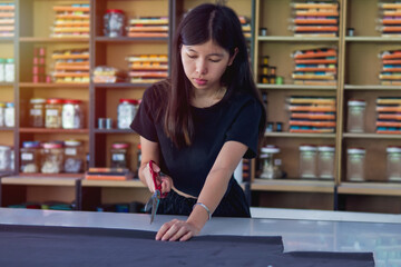 Asian woman cutting fabric with scissors at a garment factory.factory.