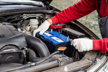a car mechanic installs a battery in a car. Battery replacement and repair