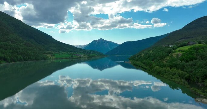 Aerial of the blue sky reflected n the calm river with mountains in the background