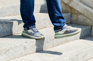 Close-up of woman's legs in jeans and sneakers going down stairs.