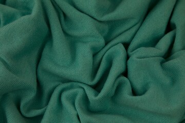 Closeup shot of green fabric with folds. © Sunanda/Wirestock Creators