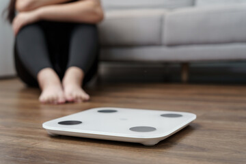 Sad woman with fat upset bored of dieting Weight loss fail  Fat diet and scale sad asian woman on weight scale at home weight control