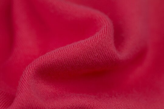 Macro shot of a red textile blanket, featuring a detailed pattern and soft texture