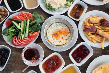 Traditional Turkish Village Breakfast with egg pan,fresh fruits,jam, fried potatoes on wooden table.Top view