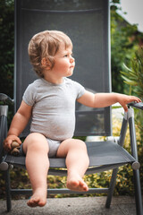 Baby im Sommer auf Gartenstuhl mit Spielfigur