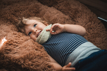 Kind liegt in braunem Kuschelkissen und lächelt