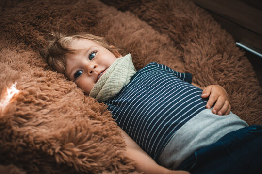 Kind liegt in braunem Kuschelkissen und schaut gedankenverloren