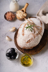 Fresh organic homemade artisan ciabatta bread with herbs, olive oil and olives on white rustic background. sourdough bread