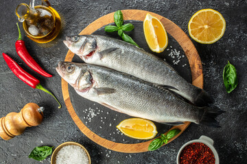 raw fish sea bass with ingredients on a dark background. banner, menu, recipe place for text, top view