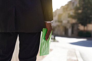 African real estate agent walking outdoors with green folder