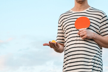 Man playing ping pong paddle table tennis paddle and ball on sky background. Motion. Mock-up copy...
