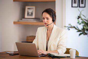 Call center assistant businesswoman wearing headset and using computer and working at home