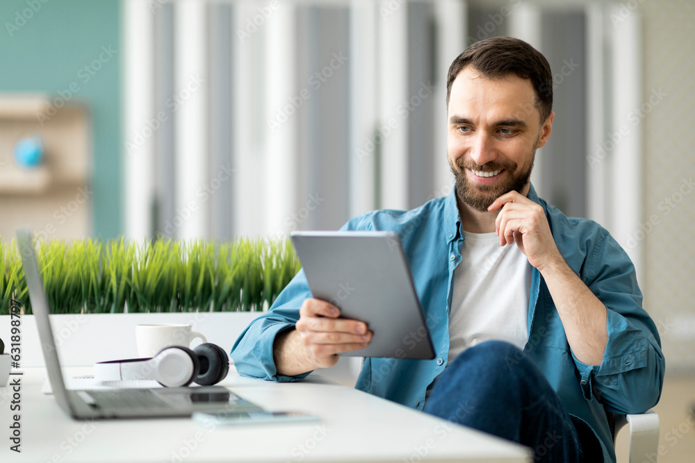 Poster modern technologies. handsome smiling man using digital tablet in office,