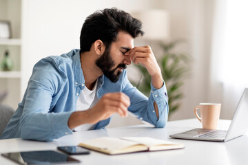 Overworking. Tired Indian Man Suffering Eyes Strain While Using Laptop At Home