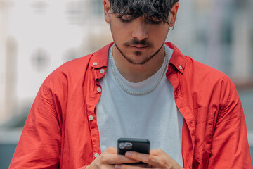 Fototapeta premium young man on the street looking at the mobile phone