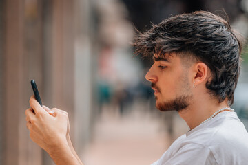 portrait of young man in the street looking at the mobile phone