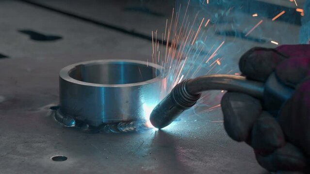 Close-up welding with sparks and metal ring. Creative. Welder welds metal ring with sparks. Sparks from welding with metal ring at factory or in forge