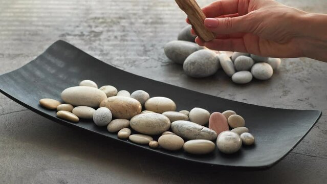 Burning Palo Santo stick with smoke on pebble stones 