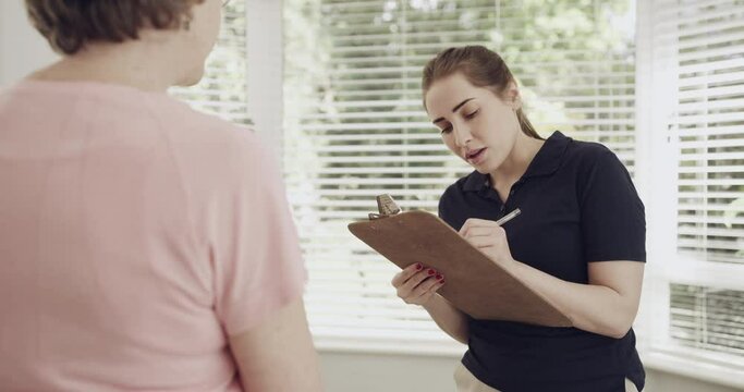 Senior woman with physiotherapist, clipboard and consultation with medical information and neck pain. Female patient with doctor, checklist of symptoms and physical therapy for injury with healthcare