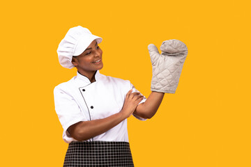 Happy Black Chef Woman Looking At Oven Mitt On Her Hand