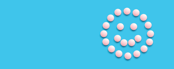 Smiling face lined with pink pills on a blue background, top view. Health care, medical pills and nutritional supplements. Pharmaceuticals