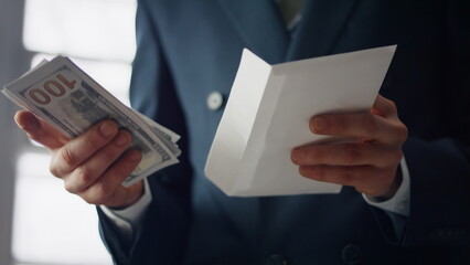 Hands putting dollars envelope close up. Man holding banknotes american currency