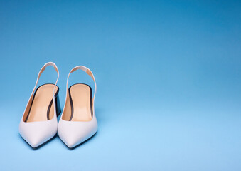 A pair of stylish pointed-toe heel shoes with open back on a gradient blue background with copy space. Shoe advertising concept.