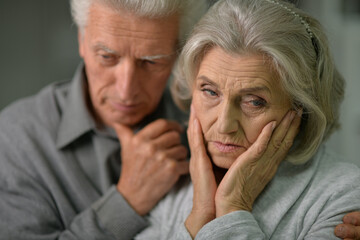 Close up portrait of sad senior couple posing at home