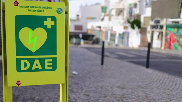 An heart defibrillator machine on the public street showing the unit on the street with cars passing by on the road located in Albufeira in Portugal