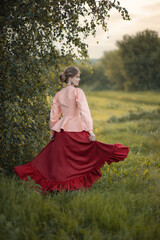 Fototapeta premium Photo of a girl in a folk costume near a birch tree.