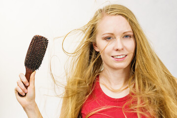 Blonde girl long blowing hair holds natural bristles brush