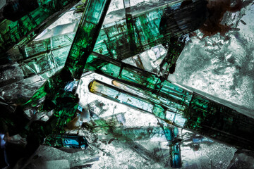 elbaite (green tourmaline) crystal on quartz backlit. macro detail texture background. close-up raw...