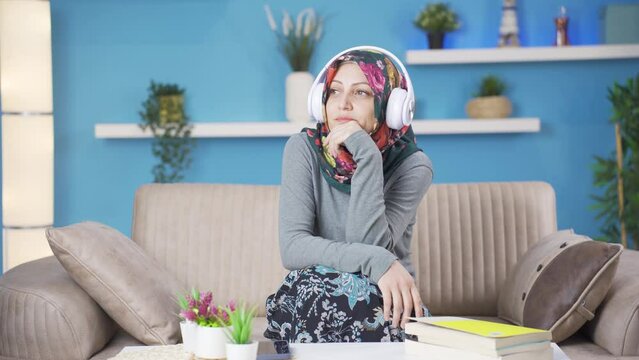 Muslim woman listening to music with headphones is unhappy and sad.