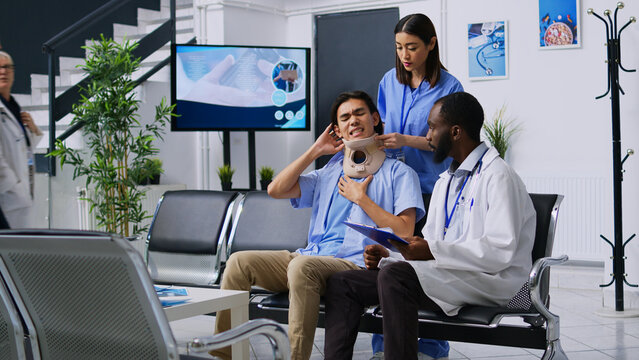 Medical staff helping injured patient to take off cervical collar while trying to recovery after neck fracture. Asian man attending checkup visit consultation in hospital reception. Medicine concept