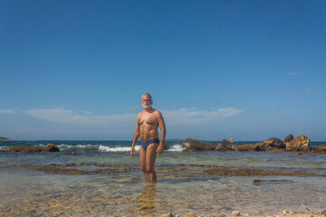 Fototapeta na wymiar mature man in the tropical beach with blue speedo