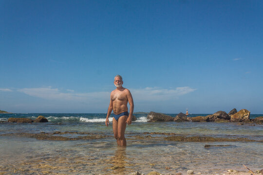 mature man in the tropical beach with blue speedo
