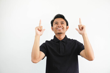 young Asian man smiling happy and pointing both hands up wearing black polo t shirt isolated on...